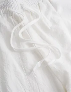 Detail shot of white linen joggers showing elastic waistband and drawstring texture