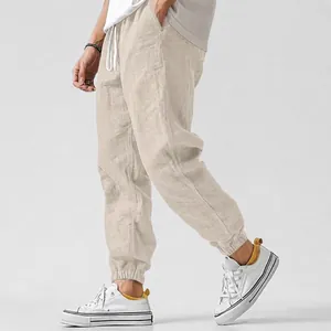 Detail view of beige cotton linen joggers showing fabric texture and elastic cuffs.
