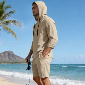 Detail van een man in een beige linnen hemd met capuchon en korte broek op een strand