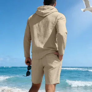Achteraanzicht van een kaki linnen herenset met capuchon en korte broek op het strand
