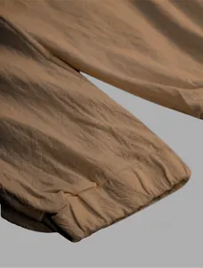 Detail of men's brown linen joggers showing elasticated tapered cuff and textured fabric