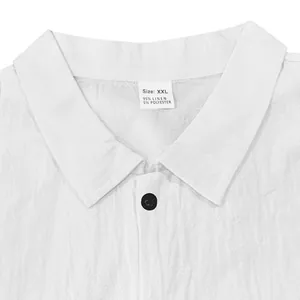 Close-up detail of white linen shirt collar showing material tag and black button