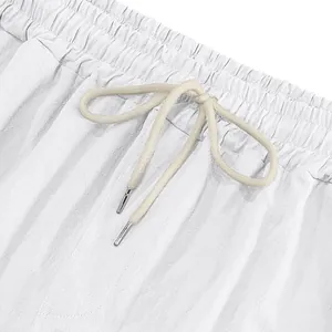 Close-up of white linen pants featuring elastic waistband and cream drawstring