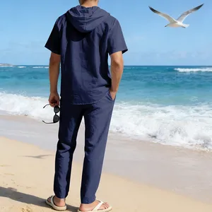 Rückansicht eines dunkelblauen Herren-Leinen-Sets mit Kapuzenhemd und Hose am Strandhintergrund