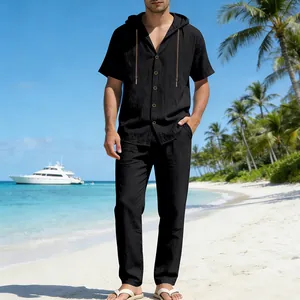 Schwarzes Herren-Leinen-Set mit Kapuzenhemd und langer Hose an einem Sandstrand
