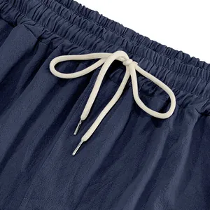 Detailed close-up showing elastic waistband and cream drawstring on navy linen pants.