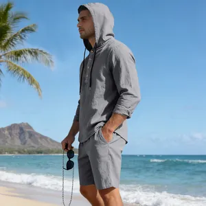 Kaukasische man in grijs linnen shirt met capuchon en korte broek op zonnig strand