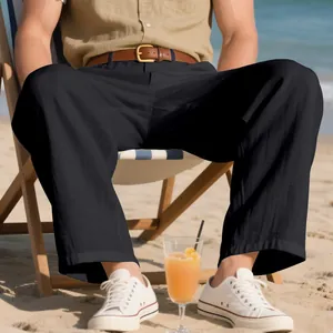 Dettaglio dei pantaloni larghi in lino nero da uomo con sneakers bianche su una spiaggia soleggiata