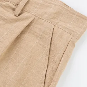 Detail shot of men's beige striped linen trousers showing pocket and fabric texture.