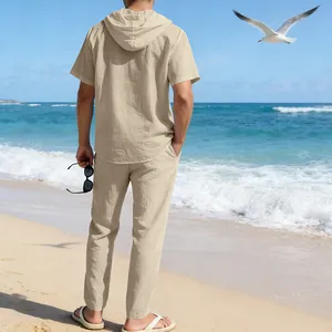 Rückansicht eines Mannes in beigem Leinen-Kapuzenhemd und Hose an einem sonnigen Strand