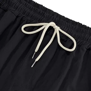 Close-up of elastic waistband with white drawstring on black linen cargo pants.