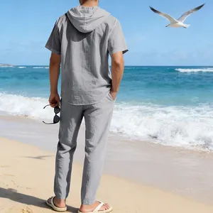 Rückansicht eines grauen Leinen-Set mit Kapuze für Herren an einem sonnigen Strand