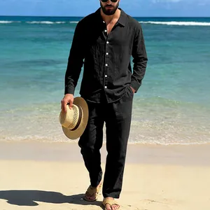 Detailed view of a man wearing a black long-sleeve linen shirt and matching pants on a beach