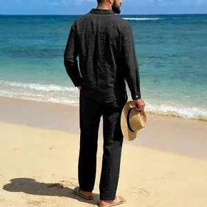 Back view of a man wearing a black linen shirt and pants suit set on a sunny beach