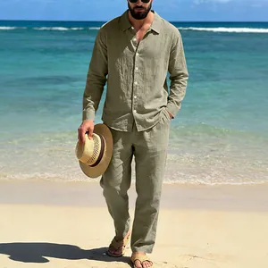 Lifestyle view of a man wearing an olive linen long-sleeve shirt and matching trousers on a beach