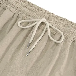 Detailed close-up of elastic waistband and drawstring on men's beige linen cargo pants.