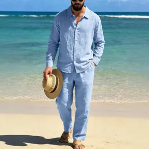 Full view of men's light blue linen shirt and pants set on a tropical beach landscape