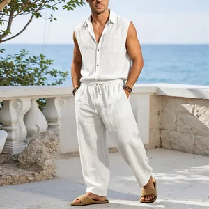 Male model wearing white sleeveless linen shirt and matching casual pants in a seaside resort.