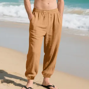 Detailed view of men's loose breathable cotton linen casual pants with drawstring on a beach
