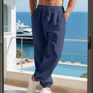 Detailed view of men's navy linen cuffed casual pants on a sunlit balcony with sea view
