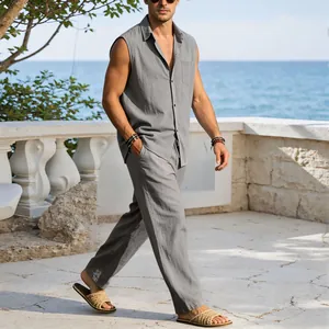 Man walking on a sunny terrace wearing a gray linen sleeveless shirt and matching trousers set