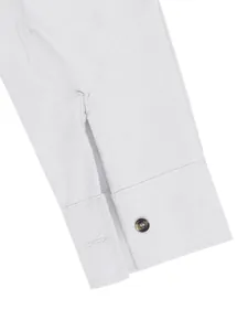 Close-up macro view of a breathable linen shirt cuff with an amber button and fine stitching