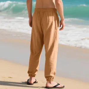 Back view of lightweight men's camel linen joggers worn on a sunny tropical beach