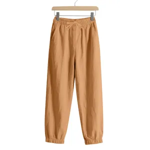 Close-up of men's ochre cotton linen joggers with elastic waist and drawstring.