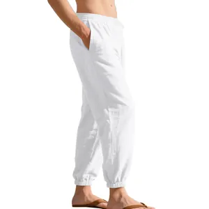 Close-up of white linen jogger pants showing texture and elastic ankle cuffs for men.
