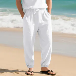 Detail of men wearing white linen casual pants with drawstring and cuffed hem on beach