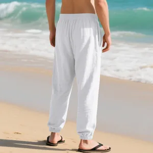 Back view of premium men's white linen joggers shown in a sunny beach vacation setting.