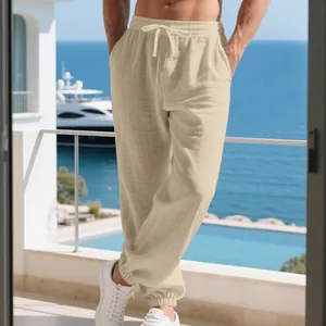 Detailed view of men's beige cotton linen pants on a sunny oceanfront balcony setting