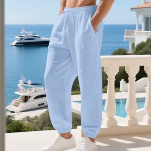 Men's light blue linen joggers with drawstring waist on a seaside balcony
