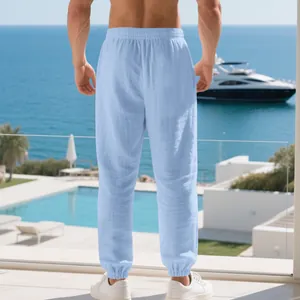 Detailed back view of men's light blue linen joggers in a luxury resort beach setting