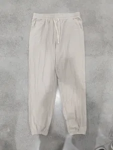 Full length front view of beige linen drawstring casual jogger pants for men on grey floor