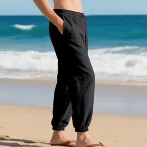 Side detail showing the texture and fit of men's black linen jogger pants on a beach