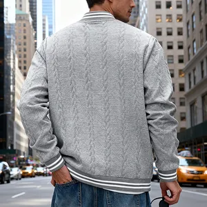 Back view detail of grey cable-knit men's varsity jacket in an urban street setting