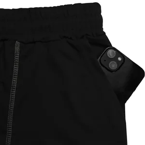 Dettaglio della tasca laterale di pantaloncini fitness neri con uno smartphone