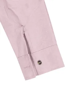 Detailed macro shot of a light pink linen shirt cuff featuring a contrast dark button