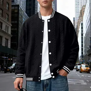 Detailed view of black cable-knit varsity jacket worn in an urban city setting