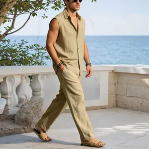 Male model walking by the sea in a khaki linen sleeveless shirt and matching trousers set
