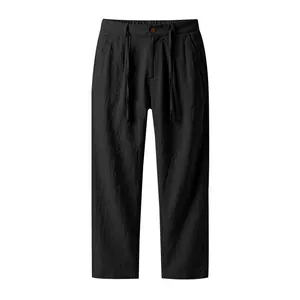 Detail shot showing the black linen fabric and drawstring waist of these men's straight trousers.