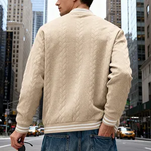 Detail view showing the back of a men's beige cable-knit bomber jacket in a city