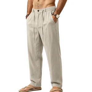 Detail view of men's loose beige linen trousers with drawstring and straight leg cut.