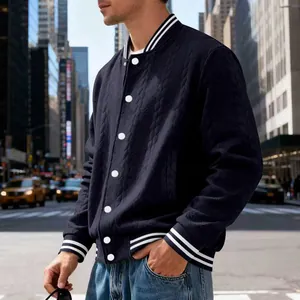 Detailed shot of man wearing navy knit varsity jacket in urban street setting