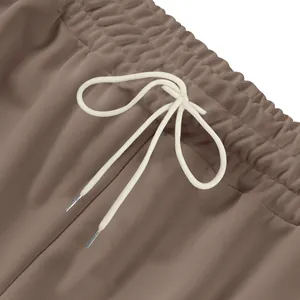 Détail en gros plan d'un jogging marron lourd avec taille élastique et cordon blanc.