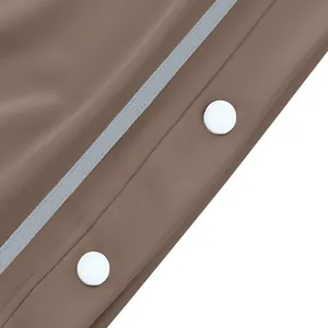Détail d'un pantalon de survêtement marron avec boutons-pression blancs et ruban