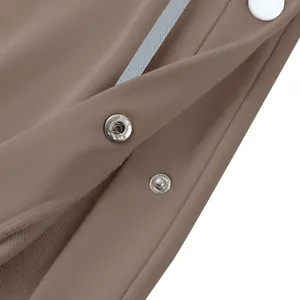 Détail des boutons-pression en métal argenté sur un pantalon de sport marron lourd