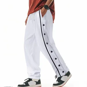Détail des pantalons de survêtement blancs avec boutons-pression latéraux noirs
