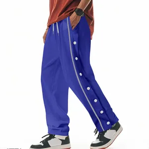 Détail du pantalon de sport hip-hop bleu avec boutons-pression latéraux blancs et rayure grise.
